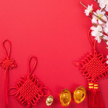 Design concept of Chinese lunar new year - Beautiful Chinese knot with plum blossom isolated on red background, flat lay, top view, overhead layout.