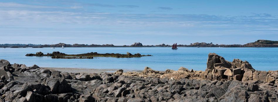 sailing vessels and rocky beach near ile de Bréhat in the north of brittany in france under blue sky