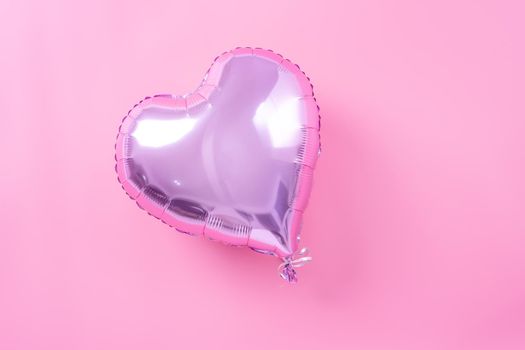 Valentine's Day minimal design concept - Beautiful real heart shape foil balloon isolated on pale pink background, top view, flat lay, overhead above photography.