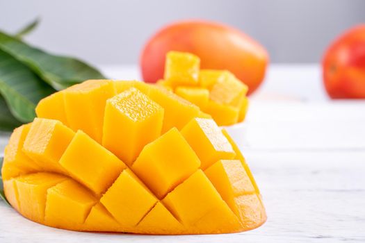 Fresh mango,beautiful chopped fruit with green leaves on bright wooden table background. Tropical fruit design concept, close up, copy space.