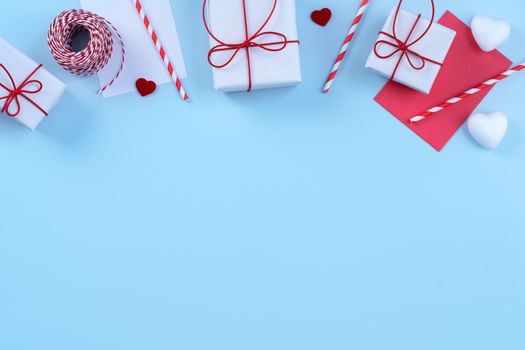 Valentine's Day, Mother's day art design concept - Red, white wrapped gift box isolated on pastel light blue color background, flat lay, top view.