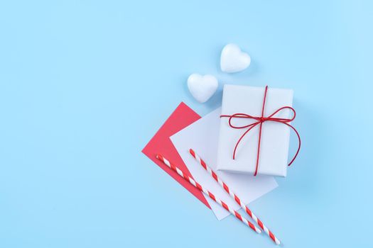 Valentine's Day, Mother's day art design concept - Red, white wrapped gift box isolated on pastel light blue color background, flat lay, top view.