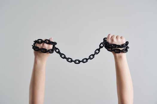 Female hands holding metal metal chain over her head