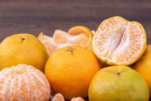 Fresh, beautiful orange color tangerine on bamboo sieve over dark wooden table. Seasonal, traditional fruit of Chinese lunar new year, close up.