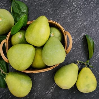 Fresh peeled pomelo, pummelo, grapefruit, shaddock on dark background in bamboo basket. Autumn seasonal fruit, top view, flat lay, tabletop shot.