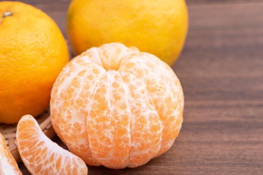 Fresh, beautiful orange color tangerine on bamboo sieve over dark wooden table. Seasonal, traditional fruit of Chinese lunar new year, close up.