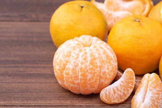 Fresh, beautiful orange color tangerine on bamboo sieve over dark wooden table. Seasonal, traditional fruit of Chinese lunar new year, close up.