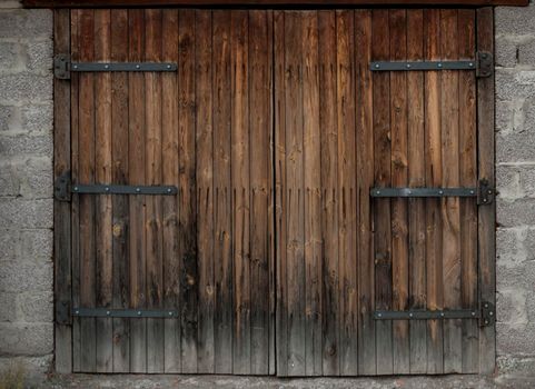 Large wooden gate and dried wood. Old brick building.