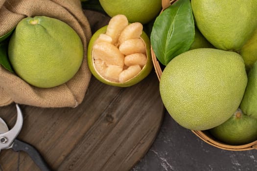 Fresh peeled pomelo, pummelo, grapefruit, shaddock on dark background in bamboo basket. Autumn seasonal fruit, top view, flat lay, tabletop shot.