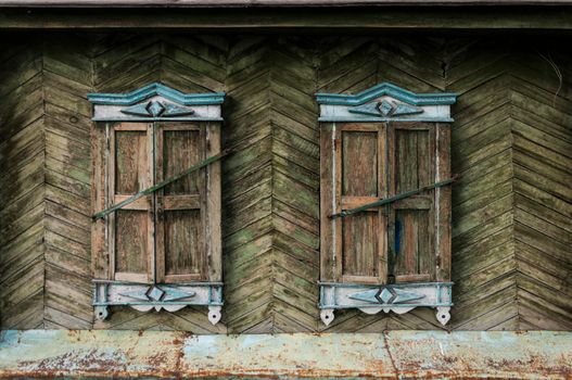 Two windows in old wall with closed shutters. Facade of ancient house. Windows with closed old wooden shutters.