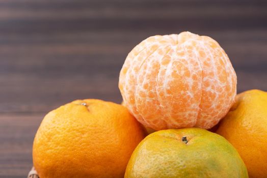 Fresh, beautiful orange color tangerine on bamboo sieve over dark wooden table. Seasonal, traditional fruit of Chinese lunar new year, close up.