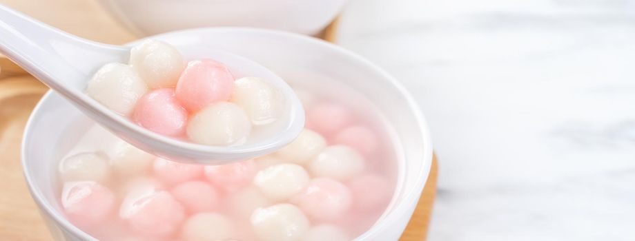 Tang yuan, tangyuan, delicious red and white rice dumpling balls in a small bowl. Asian traditional festive food for Chinese Winter Solstice Festival, close up.