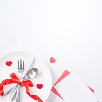 Valentine's Day, Mother's Day, holiday dating meal, banquet design concept - White plate and red ribbon on marble background, top view, flat lay.