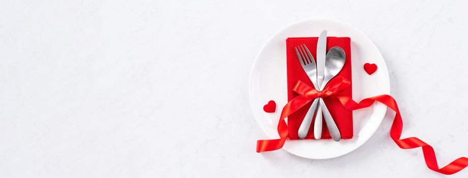 Valentine's Day, Mother's Day, holiday dating meal, banquet design concept - White plate and red ribbon on marble background, top view, flat lay.