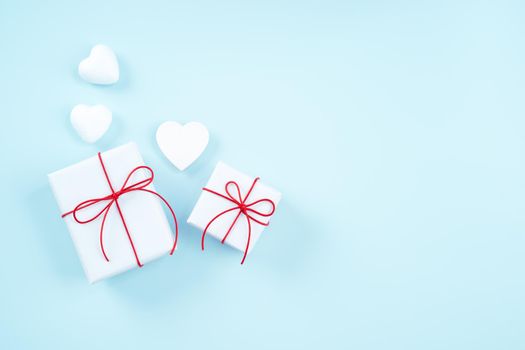 Valentine's Day, Mother's day art design concept - Red, white wrapped gift box isolated on pastel light blue color background, flat lay, top view.