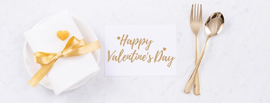 Valentine's Day holiday dating meal, banquet greeting card design concept - White plate and golden color tableware on marble background, top view, flat lay.