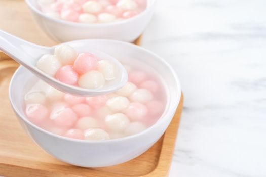 Delicious tang yuan, red and white rice dumpling balls in a small bowl. Asian traditional festive food for Chinese Winter Solstice Festival, close up.