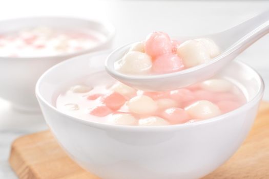 Delicious tang yuan, red and white rice dumpling balls in a small bowl. Asian traditional festive food for Chinese Winter Solstice Festival, close up.