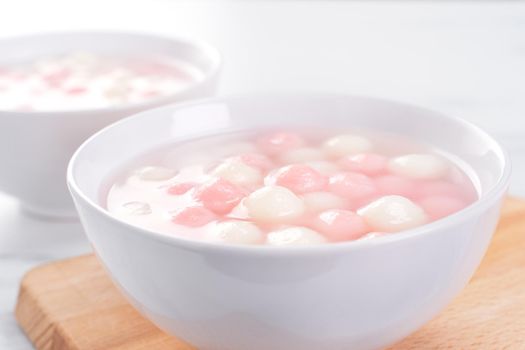 Tang yuan, tangyuan, delicious red and white rice dumpling balls in a small bowl. Asian traditional festive food for Chinese Winter Solstice Festival, close up.