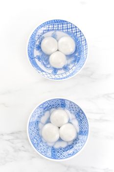 Tang yuan, tangyuan, yuanxiao in a small bowl stuffed with sesame fillings, top view, flat lay. Delicious asian food rice dumpling balls for festival.