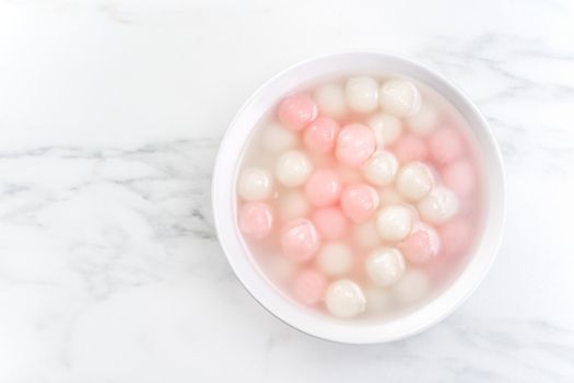 Tang yuan, tangyuan, delicious red and white rice dumpling balls in a small bowl, top view, flat lay. Asian festive food for Winter Solstice Festival.