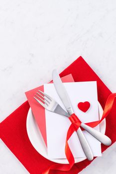 Valentine's Day, Mother's Day, holiday dating meal, banquet design concept - White plate and red ribbon on marble background, top view, flat lay.