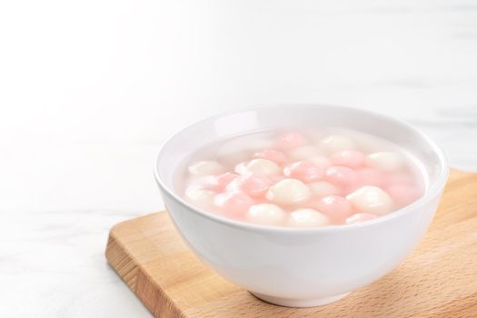 Delicious tang yuan, red and white rice dumpling balls in a small bowl. Asian traditional festive food for Chinese Winter Solstice Festival, close up.