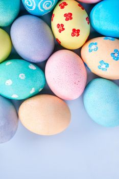 Colorful Easter eggs dyed by colored water with beautiful pattern on a pale blue background, design concept of holiday activity, top view, copy space.