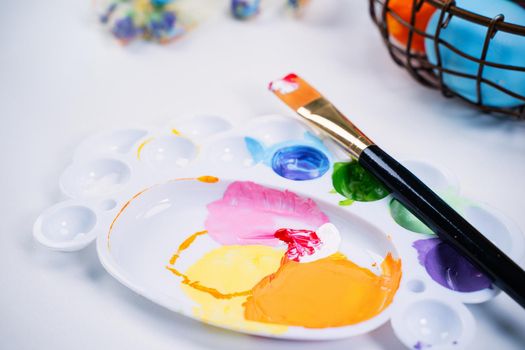 Design concept - Preparing for Easter celebration, painting Easter eggs with colorful Acrylic pigment color dyestuff in palette, close up, lifestyle.