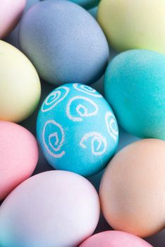 Colorful Easter eggs dyed by colored water with beautiful pattern on a pale blue background, design concept of holiday activity, top view, full frame.