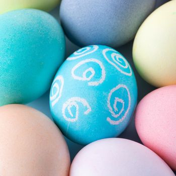 Colorful Easter eggs dyed by colored water with beautiful pattern on a pale blue background, design concept of holiday activity, top view, full frame.
