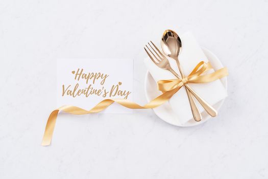 Valentine's Day holiday dating meal, banquet greeting card design concept - White plate and golden color tableware on marble background, top view, flat lay.