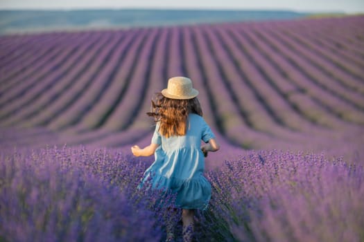 Lavender sunset girl. A girl in a blue dress with flowing hair in a hat runs through a lilac field of lavender. Aromatherapy travel