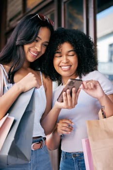 Women friends, phone and shopping in city with sale, choice and ecommerce discount on web, app and together. Black woman, smile and online shopping for e commerce with bags in metro for fashion store.