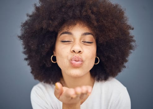Kissing, love and romance with a black woman blowing a kiss in studio on a gray background for romantic affection. Beauty, lips and flirt with an attractive young female making a mouth gesture.