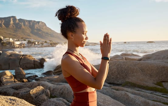 Woman, prayer hands or meditation by sunrise beach, ocean or sea water for relax fitness, workout or exercise in spiritual wellness. Yogi, praying mudra or zen person in mind training or nature peace.