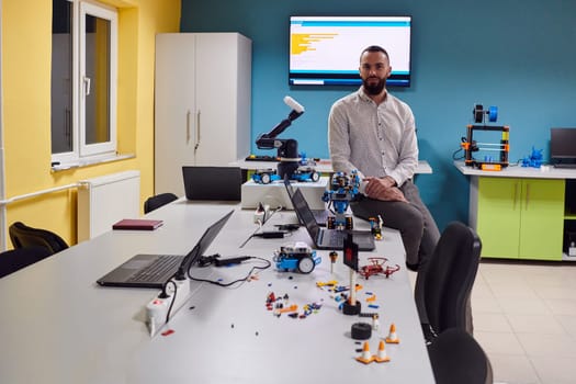 A bearded man in a modern robotics laboratory, immersed in research and surrounded by advanced technology and equipment