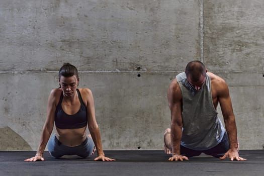 An attractive couple in the gym engaging in various stretching exercises together, showcasing their dedication to fitness, flexibility, and overall wellbeing. With synchronized movements, they demonstrate coordination, balance, and endurance while supporting and motivating each other on their fitness journey.