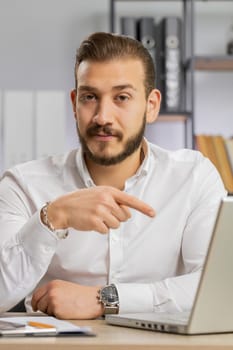 Business man working online on laptop, finishing work, positive feedback, like, approving application, good offer sale advertisement. Freelancer guy at office looking at camera, talking. Vertical