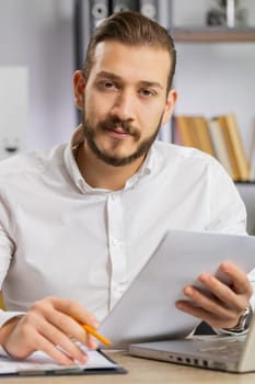 Businessman ceo reading business contract, planning project, analyzing resume, satisfied with good paperwork results. Man at office looking at camera talking, online conversation interview. Vertical