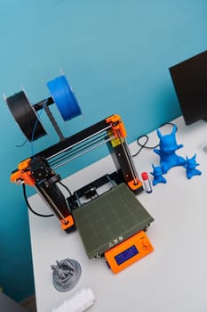 Modern 3d printer for creating 3d models and materials on the table in the laboratories next to the computer. High quality photo