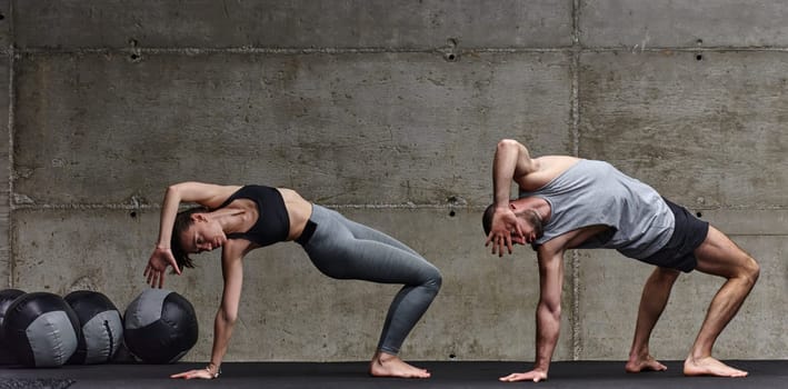 An attractive couple in the gym engaging in various stretching exercises together, showcasing their dedication to fitness, flexibility, and overall wellbeing. With synchronized movements, they demonstrate coordination, balance, and endurance while supporting and motivating each other on their fitness journey.