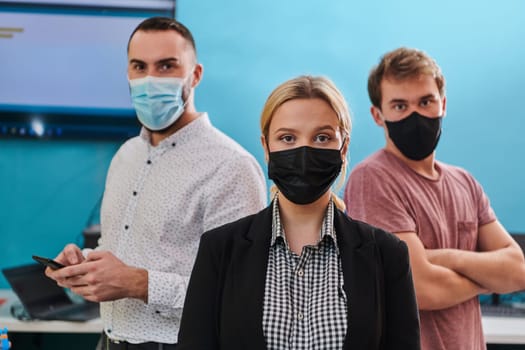 A group of colleagues stand ingin a robotics laboratory, arms crossed, wearing protective masks, symbolizing their teamwork and commitment to technological innovation and scientific research