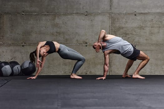 An attractive couple in the gym engaging in various stretching exercises together, showcasing their dedication to fitness, flexibility, and overall wellbeing. With synchronized movements, they demonstrate coordination, balance, and endurance while supporting and motivating each other on their fitness journey.