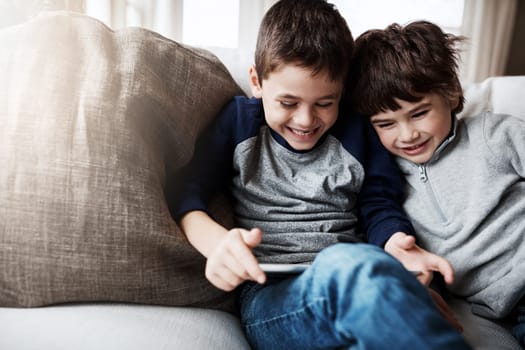 Boy siblings, tablet and sofa with laugh, funny meme and digital app for gaming, streaming or comedy. Kids, couch and mobile tech on social media, video or comic movie in family home for love bonding.