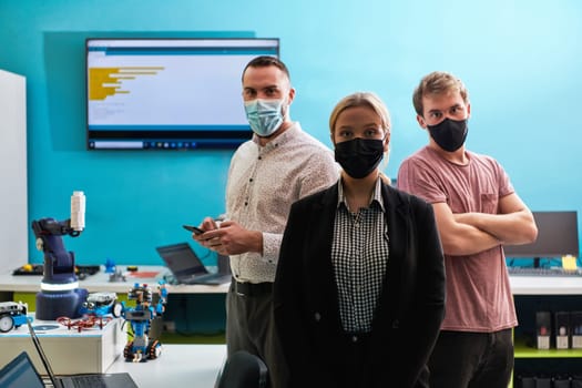 A group of colleagues stand ingin a robotics laboratory, arms crossed, wearing protective masks, symbolizing their teamwork and commitment to technological innovation and scientific research