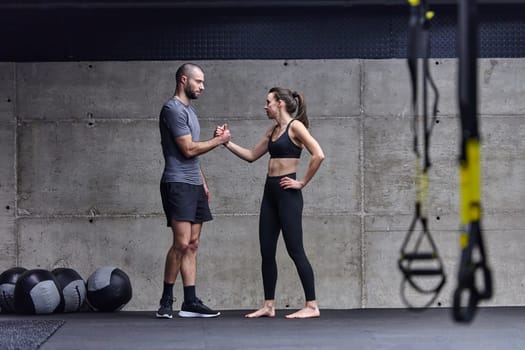 Muscular man and fit woman in a conversation before commencing their training session in a modern gym