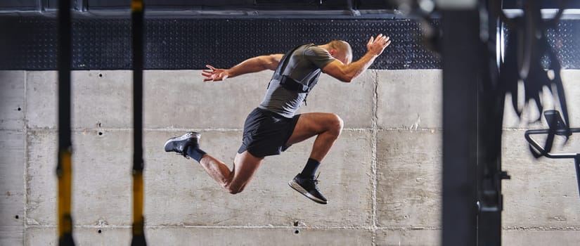 A muscular man captured in air as he jumps in a modern gym, showcasing his athleticism, power, and determination through a highintensity fitness routine.