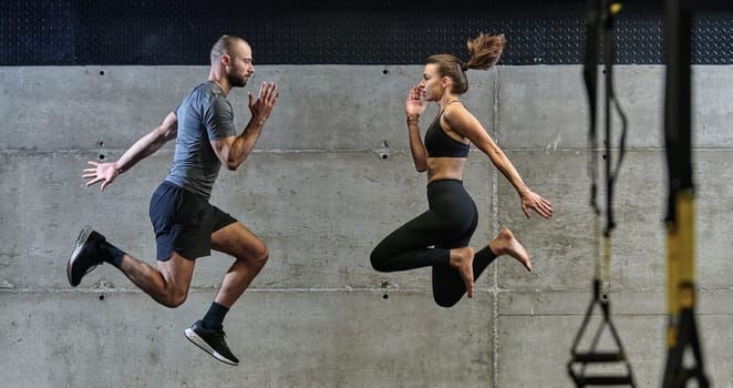 A fit couple exercising various types of jumps in a modern gym, demonstrating their physical fitness, strength, and athletic performance.