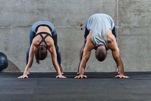 An attractive couple in the gym engaging in various stretching exercises together, showcasing their dedication to fitness, flexibility, and overall wellbeing. With synchronized movements, they demonstrate coordination, balance, and endurance while supporting and motivating each other on their fitness journey.